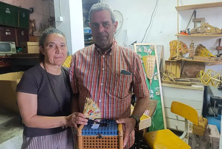 Conjunto de leques de palha e uma mala de folha de flandres verde em exposição